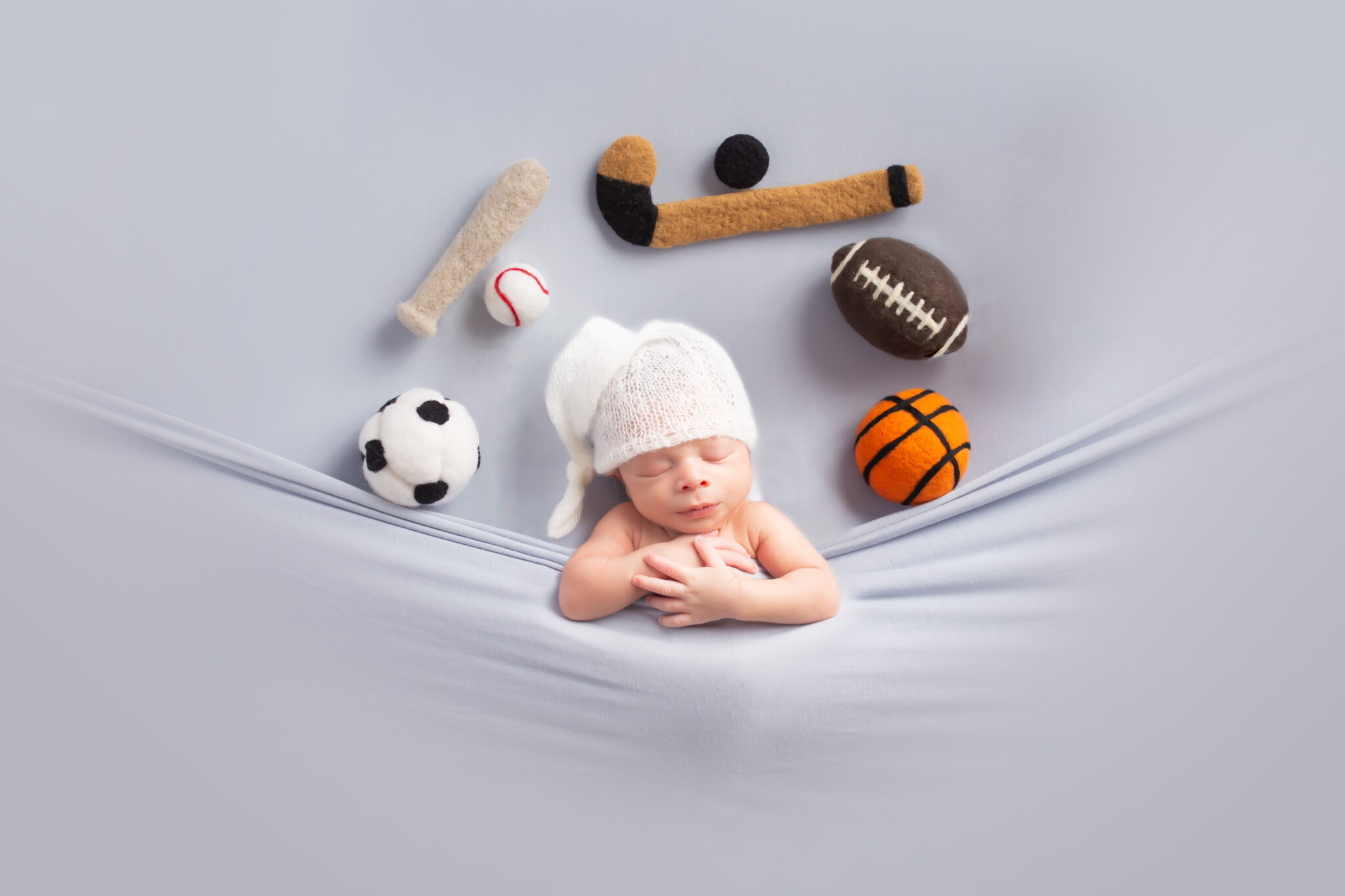Dallas newborn photographer poses baby in tucked in pose with all sports balls and objects