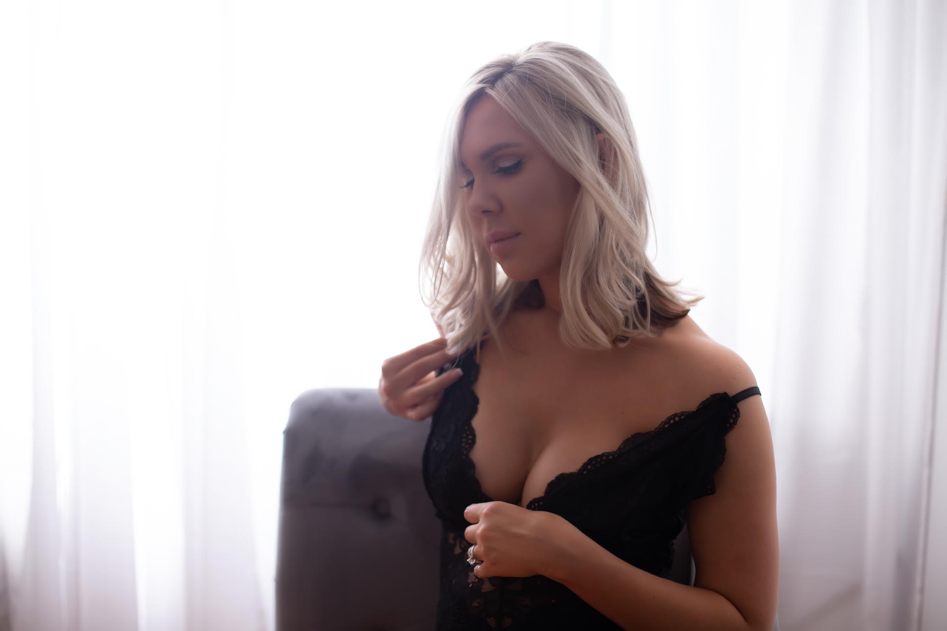 dallas boudoir photographer shares studio pictures of woman seated near sheer white curtains in black lingerie