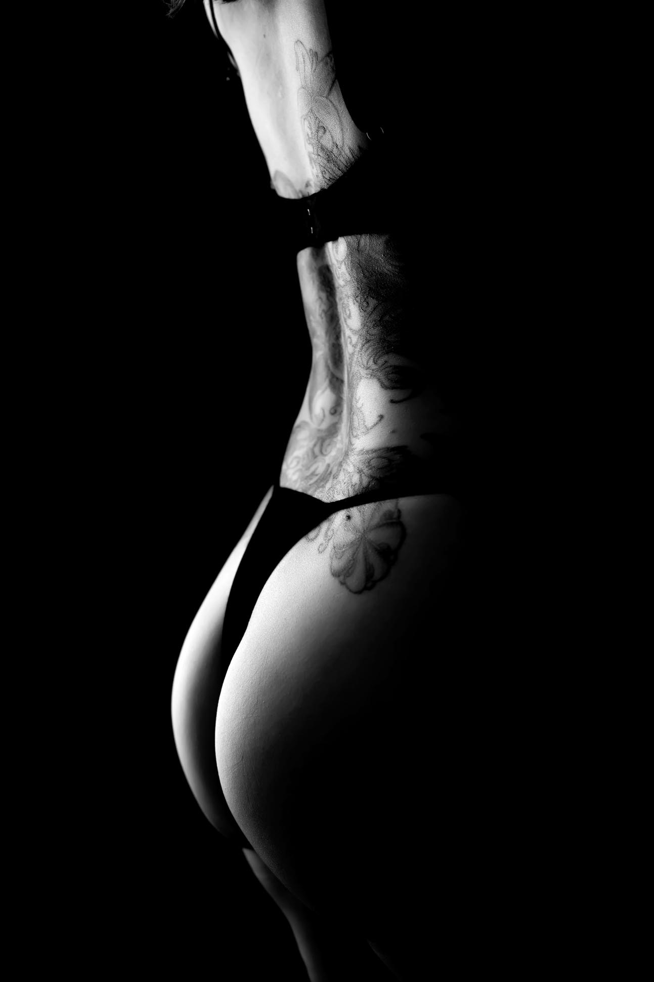 Silhouette of woman's derriere with black lingerie shot in black and white during Dallas boudoir photography session.