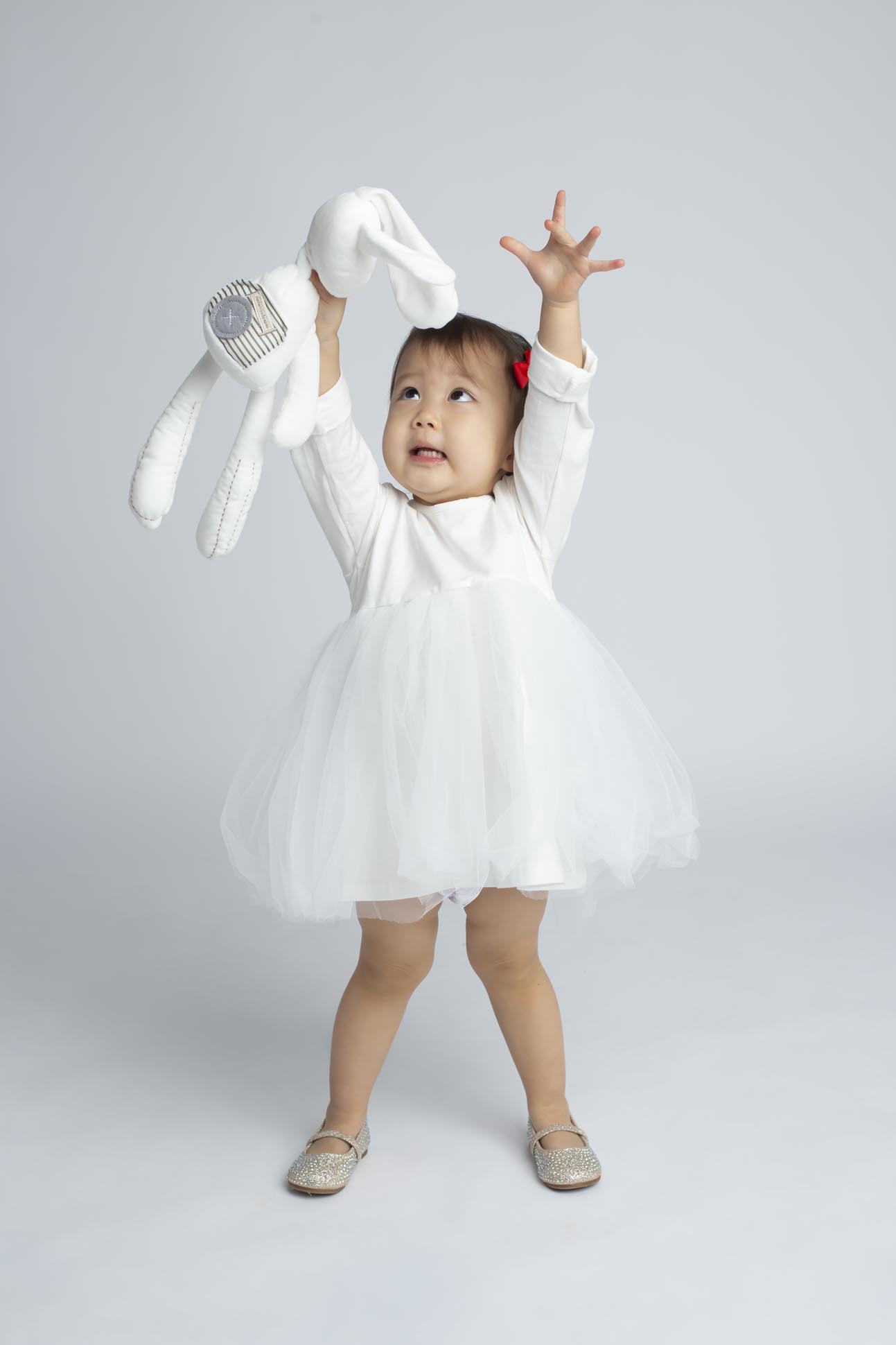 Dallas child photographer displays portrait of young girl in white dress holding a play bunny during indoor portrait photography session