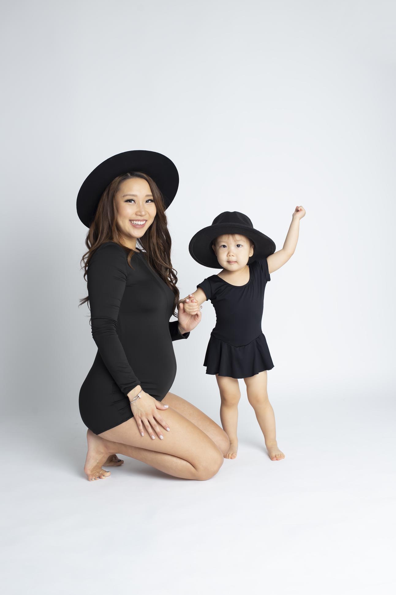 Dallas maternity photographer shares portrait of pregnant mom with young daughter both are wearing black on a white background