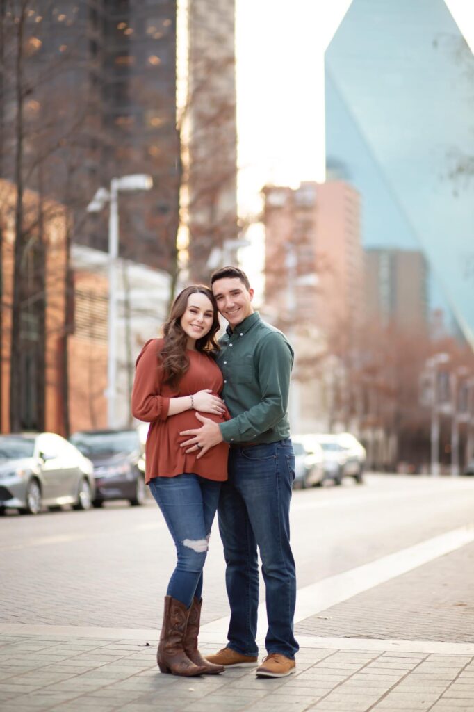 Expectant couple poses during their maternity photography session with Dallas Maternity Photographer Mod L Photography wearing casual clothes in downtown Dallas