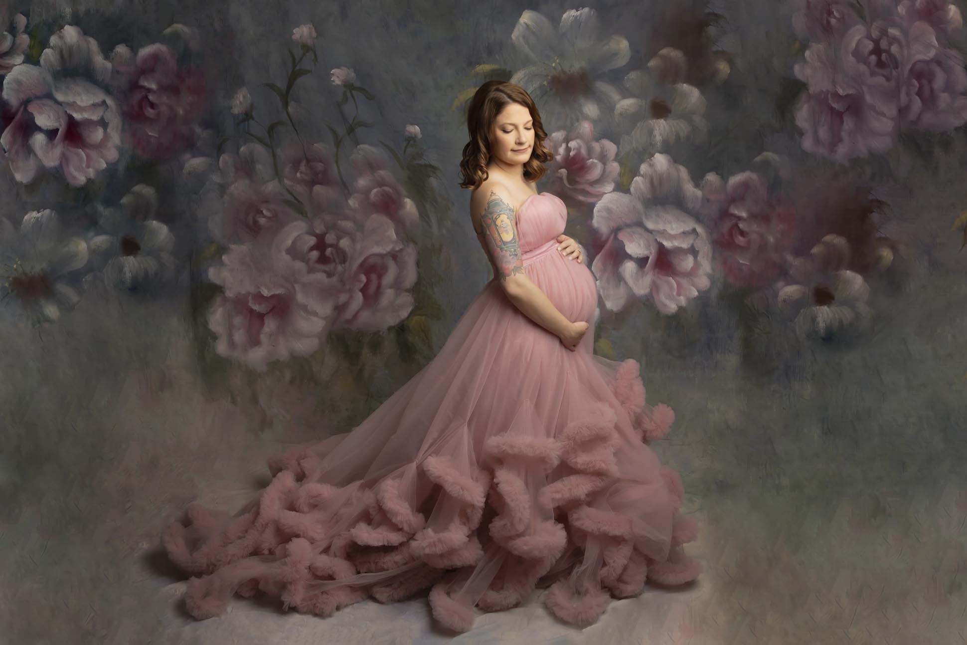 Dallas maternity photographer displays portrait of pregnant mom wearing pink princess style ballgown posing on a hand painted floral backdrop
