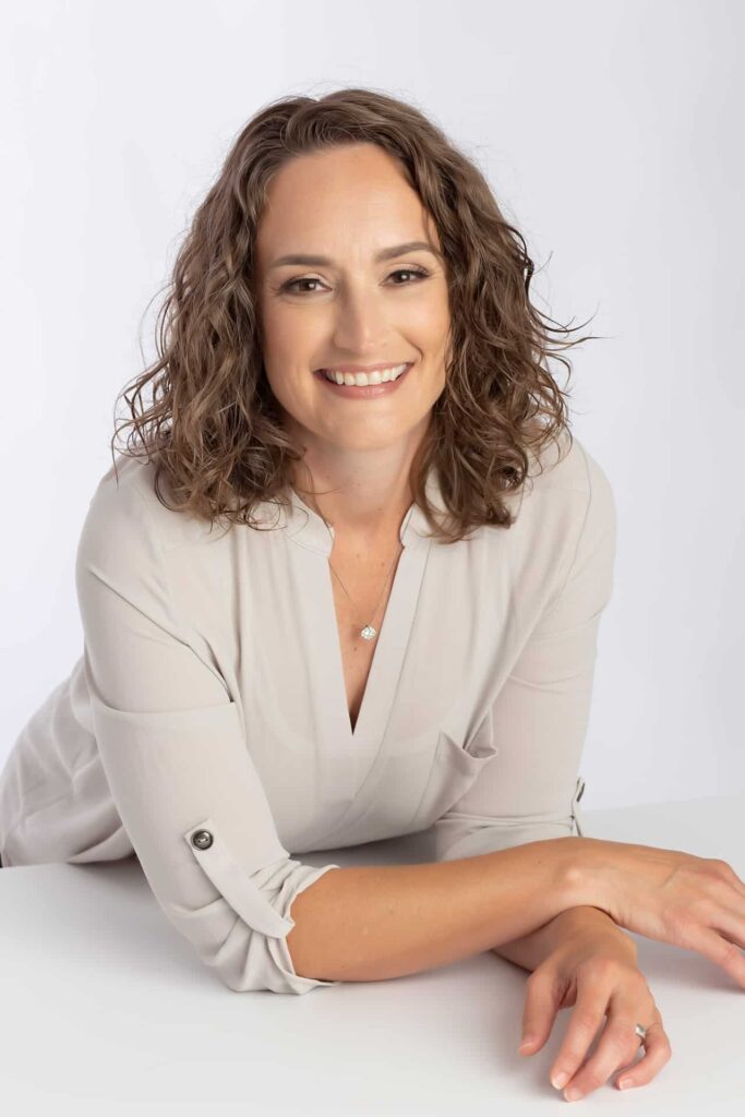 Dallas headshot photographer captures image of female executive wearing cream colored 3/4 length sleeve blouse on light gray background