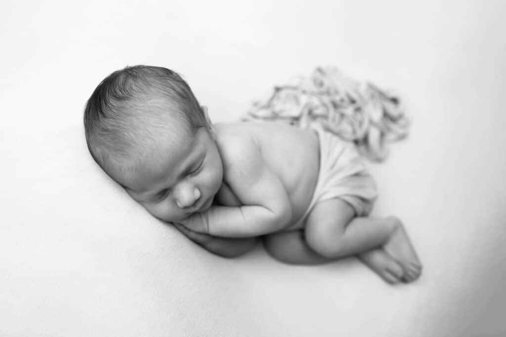 Dallas newborn photographer poses baby on light colored background in classic black and white minimalist image and tells how to prepare for your newborn photography session