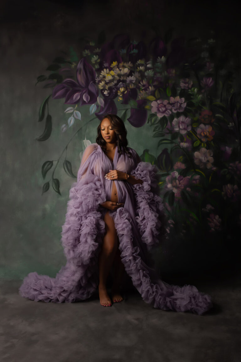 Maternity photography session with mother posing on hand painted floral backdrop wearing lavender gown in studio with Mod L Photography of Dallas Texas