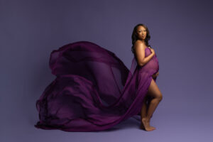 Mother to be photographed on lavender background draped in deep purple flowing fabric in maternity photography session in Dallas Texas with Mod L Photography